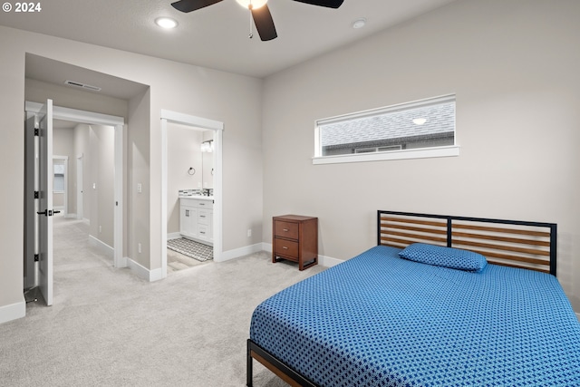 bedroom with light carpet, ensuite bathroom, and ceiling fan