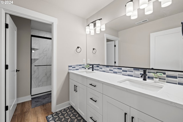 bathroom featuring vanity, hardwood / wood-style floors, walk in shower, and backsplash