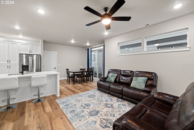 living room with light hardwood / wood-style flooring and ceiling fan