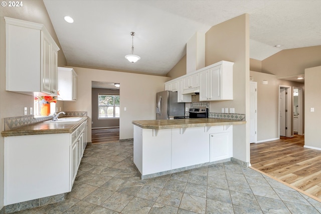 kitchen with kitchen peninsula, lofted ceiling, white cabinetry, sink, and stainless steel appliances