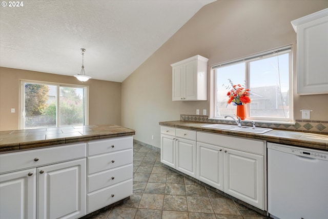 kitchen featuring white cabinets, white dishwasher, vaulted ceiling, tile counters, and sink