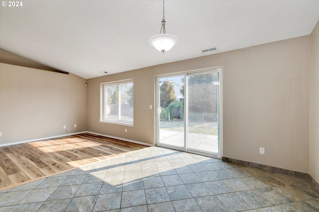 empty room with lofted ceiling, a textured ceiling, and hardwood / wood-style flooring