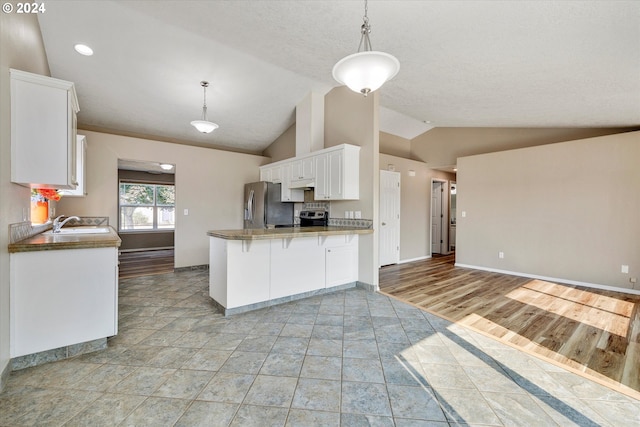 kitchen with light hardwood / wood-style floors, stainless steel appliances, lofted ceiling, and white cabinets