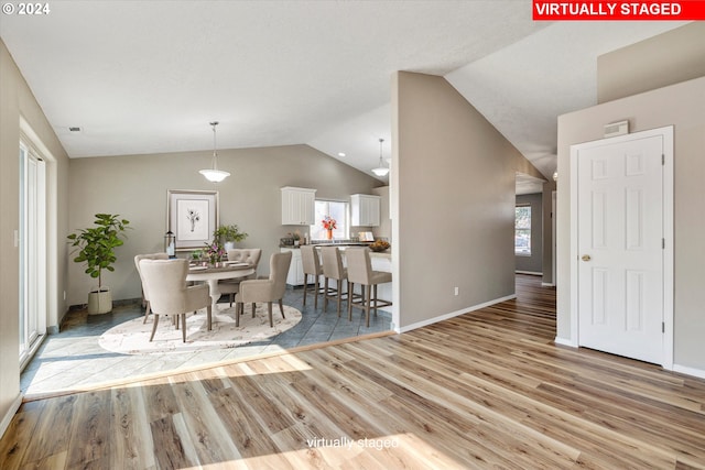 dining room with lofted ceiling and light wood-type flooring