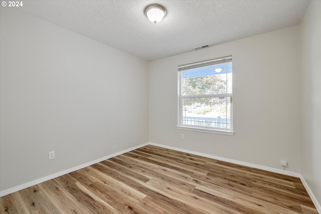 spare room featuring a textured ceiling and wood-type flooring