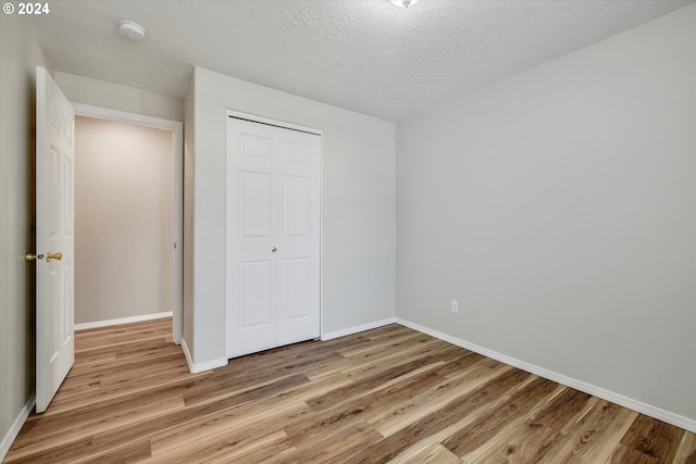 unfurnished bedroom with a closet, a textured ceiling, and light wood-type flooring