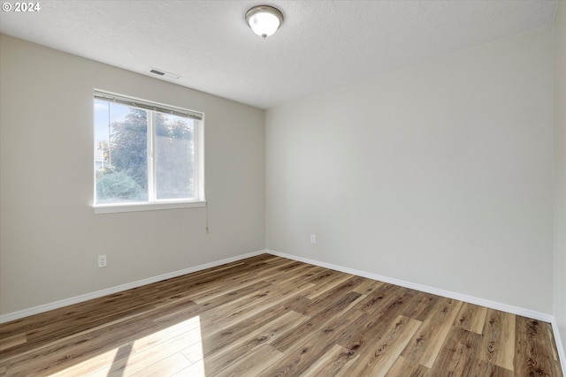 unfurnished room featuring a textured ceiling and light wood-type flooring