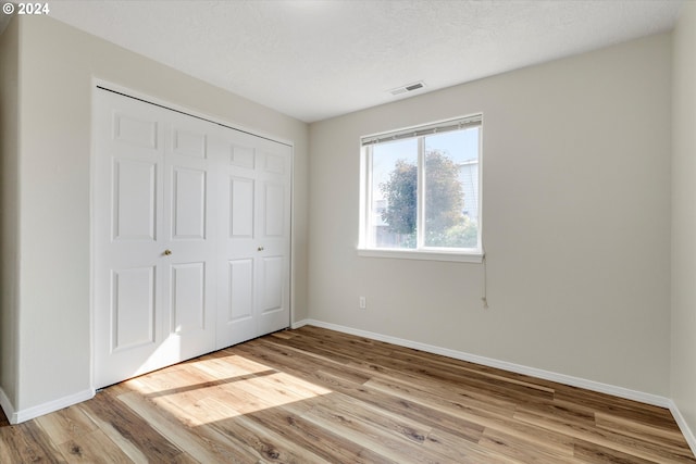 unfurnished bedroom with a closet, a textured ceiling, and light hardwood / wood-style floors