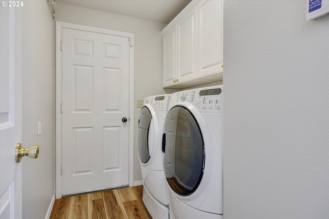 laundry room with light hardwood / wood-style flooring, washer and dryer, and cabinets