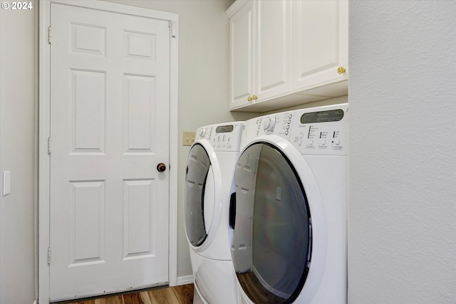 clothes washing area featuring cabinets, washer and dryer, and dark hardwood / wood-style flooring