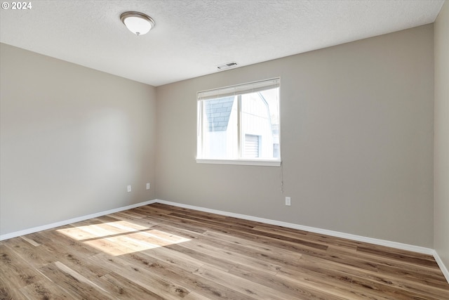 empty room featuring a textured ceiling and light hardwood / wood-style flooring