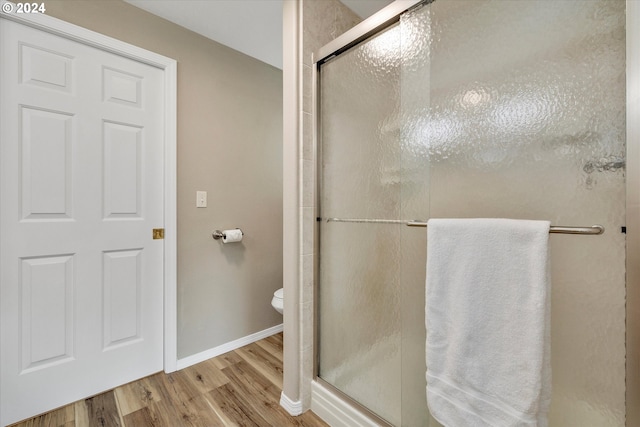 bathroom with a shower with door, toilet, and hardwood / wood-style floors