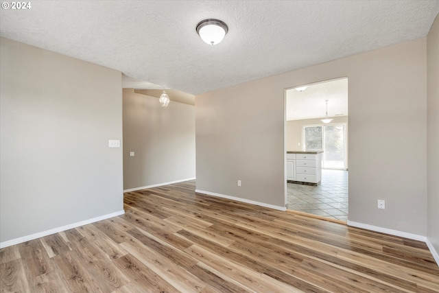 unfurnished room featuring wood-type flooring and a textured ceiling