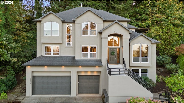 view of front of house with a garage, concrete driveway, and stucco siding