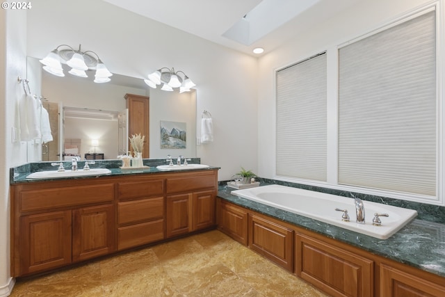 full bath featuring double vanity, a skylight, a sink, and a bath