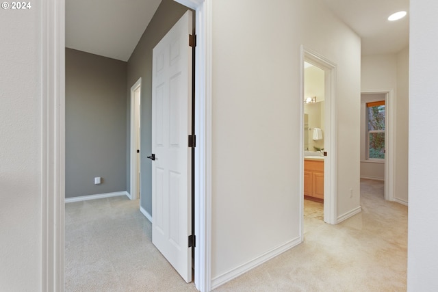 hall with recessed lighting, light colored carpet, and baseboards