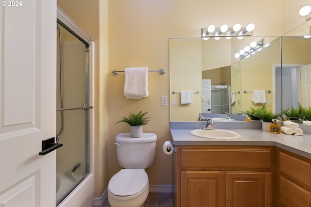 full bathroom featuring vanity, enclosed tub / shower combo, and toilet