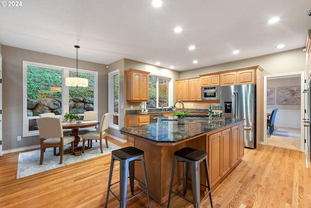 kitchen featuring appliances with stainless steel finishes, a center island, hanging light fixtures, and light wood-type flooring