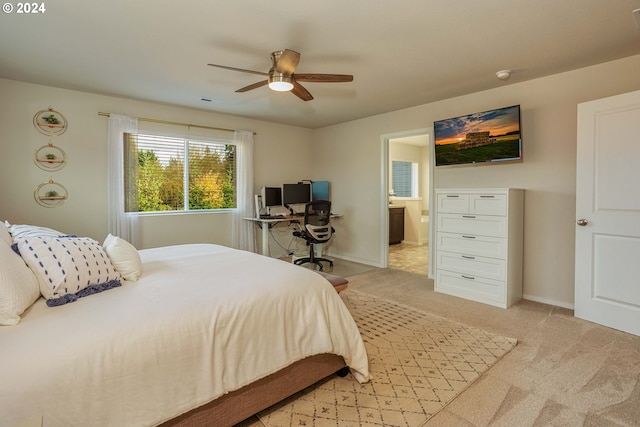 bedroom featuring ceiling fan, ensuite bath, and light colored carpet