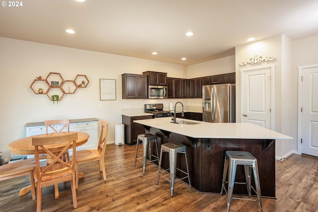 kitchen with a center island with sink, dark wood-type flooring, a kitchen bar, and stainless steel appliances