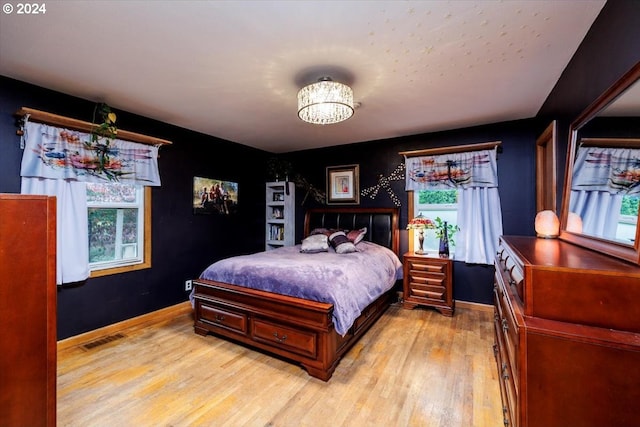 bedroom featuring an inviting chandelier and light hardwood / wood-style flooring