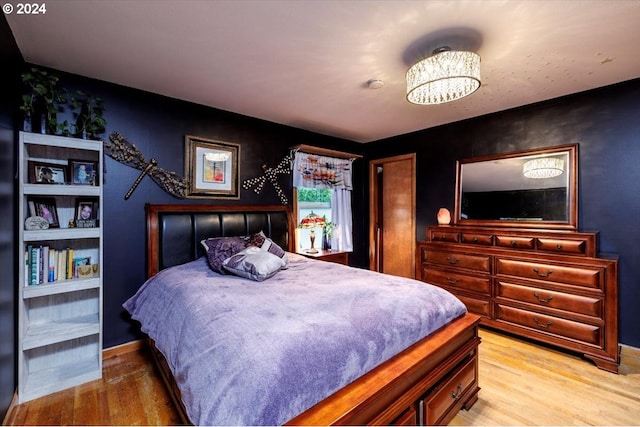 bedroom with light hardwood / wood-style floors and a notable chandelier