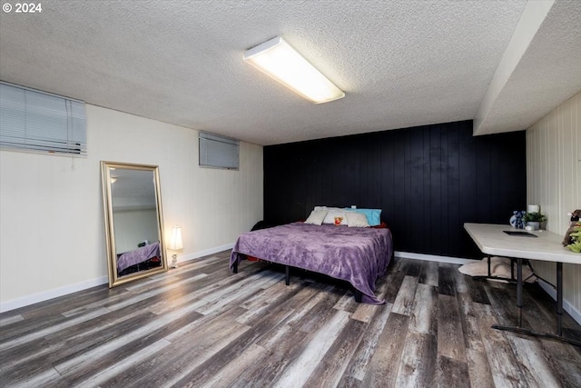 bedroom featuring a textured ceiling, dark hardwood / wood-style floors, and wood walls