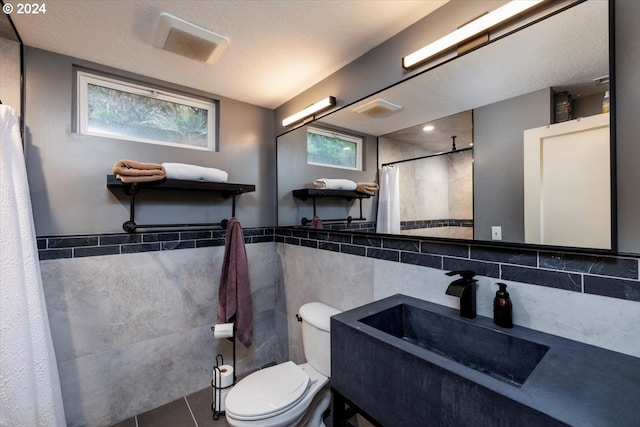 bathroom featuring tile walls, tile patterned floors, a shower with shower curtain, and toilet