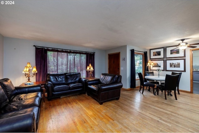 living room featuring ceiling fan, a textured ceiling, and light wood-type flooring