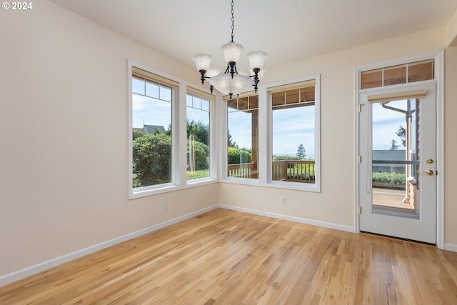 unfurnished dining area featuring a chandelier, light hardwood / wood-style floors, and a wealth of natural light