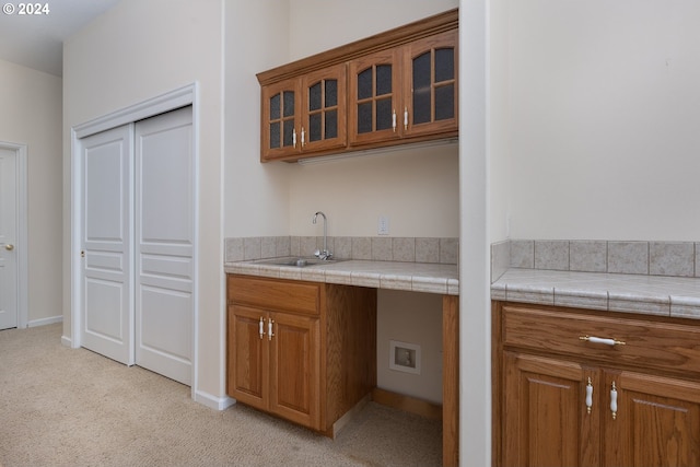 kitchen with light carpet, tile counters, and sink