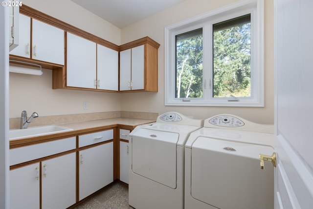 laundry area with cabinets, washer and clothes dryer, and sink