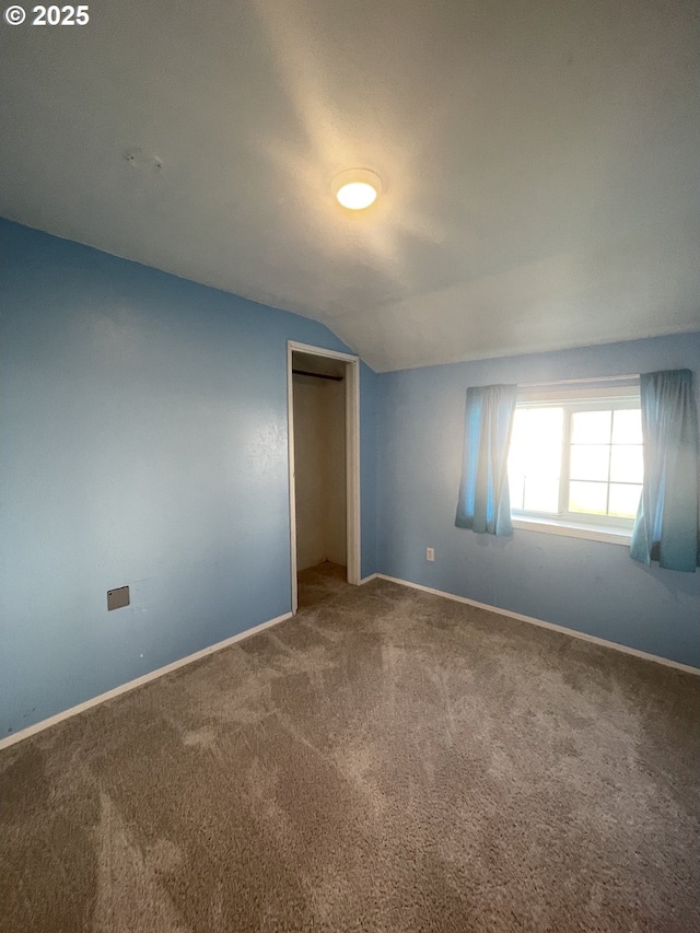 unfurnished bedroom featuring lofted ceiling, carpet floors, and a closet