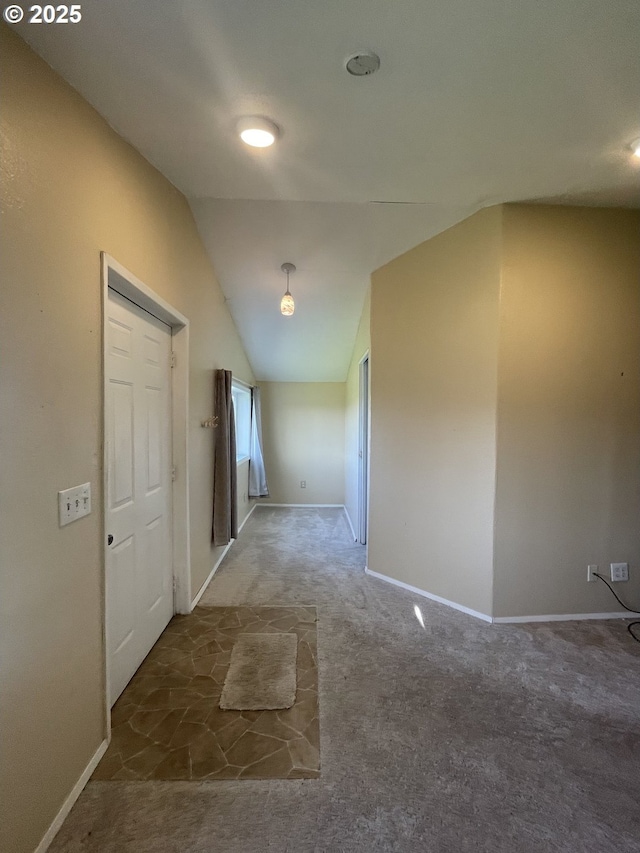 hallway featuring dark colored carpet and vaulted ceiling