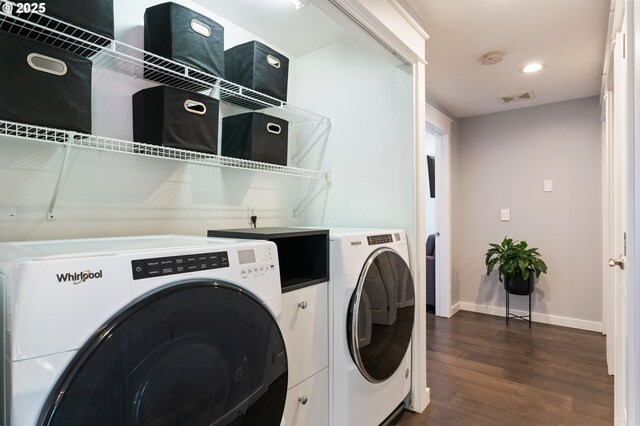 laundry room featuring washing machine and clothes dryer, visible vents, baseboards, dark wood finished floors, and laundry area