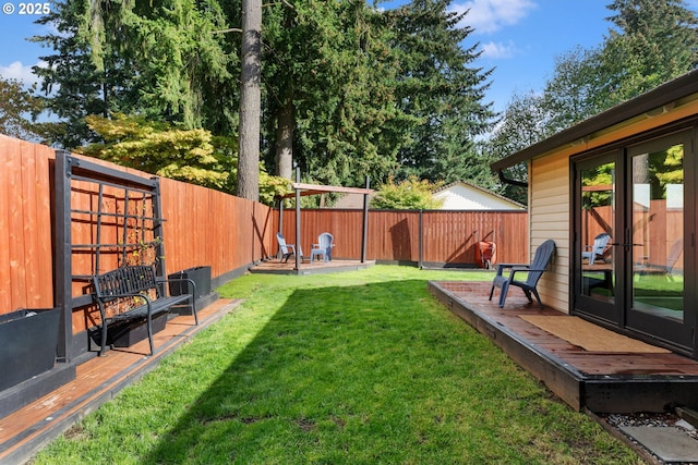 view of yard featuring french doors, a wooden deck, and a fenced backyard