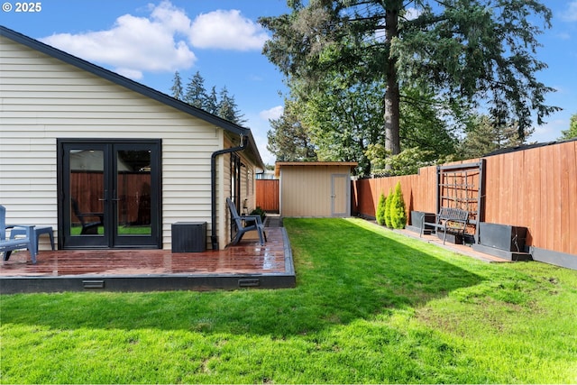 view of yard featuring french doors, a deck, a fenced backyard, an outbuilding, and a storage unit