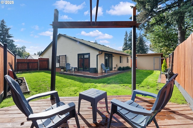 rear view of property featuring a wooden deck, a yard, an outdoor structure, and a fenced backyard