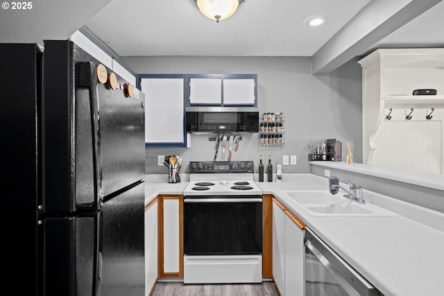 7143 SW Sagert St Unit 104, Tualatin, OR 97062 - kitchen featuring black appliances, a sink, white cabinets, light countertops, and wood finished floors