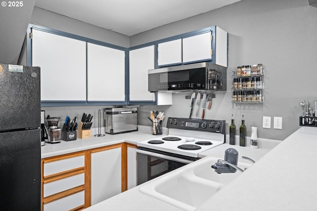 7143 SW Sagert St Unit 104, Tualatin, OR 97062 - kitchen with range with electric cooktop, freestanding refrigerator, white cabinets, light countertops, and a sink