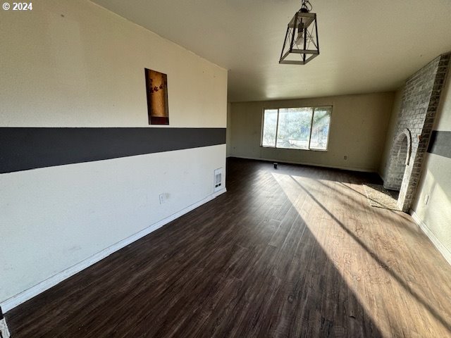 unfurnished living room with a brick fireplace and dark hardwood / wood-style flooring