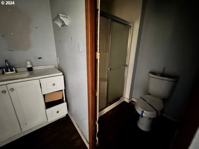 bathroom with a shower with door, vanity, wood-type flooring, and toilet