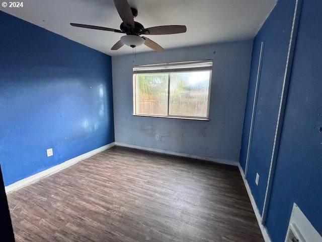 empty room with dark wood-type flooring and ceiling fan