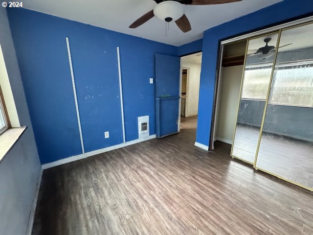 unfurnished bedroom featuring dark wood-type flooring, ceiling fan, and a closet