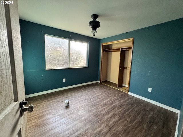 unfurnished bedroom with dark wood-type flooring and a closet