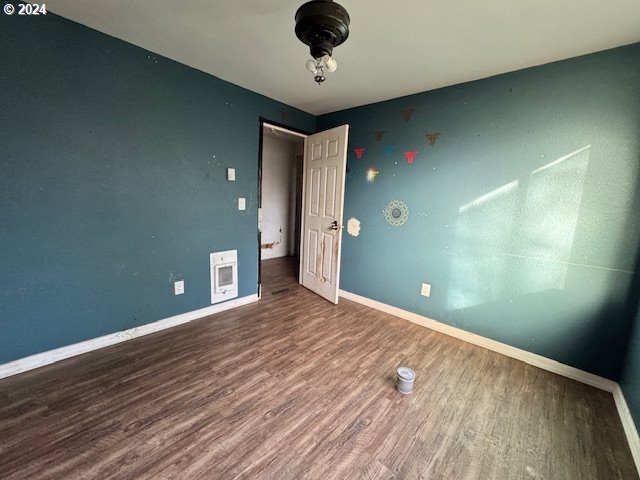 unfurnished bedroom featuring heating unit and hardwood / wood-style floors