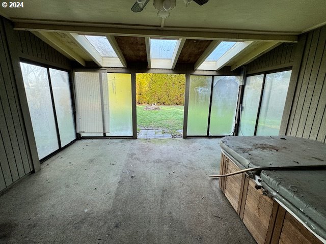 unfurnished sunroom with lofted ceiling with skylight and a healthy amount of sunlight