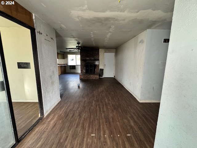 unfurnished living room featuring dark hardwood / wood-style flooring, a fireplace, and ceiling fan