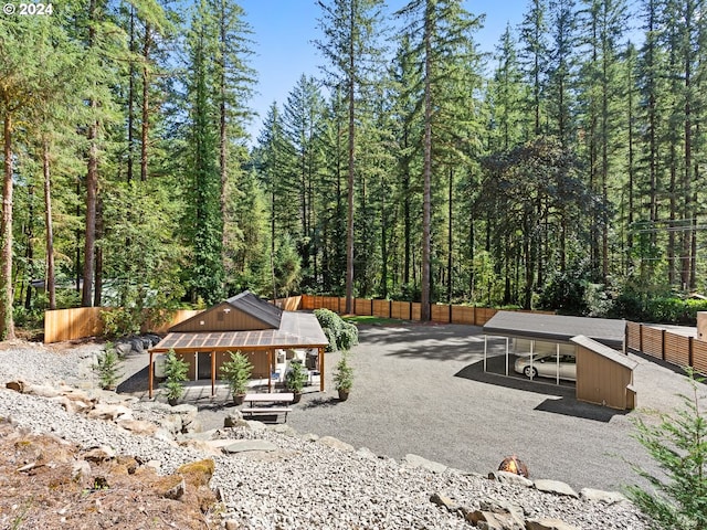 view of community with driveway, fence, and a view of trees