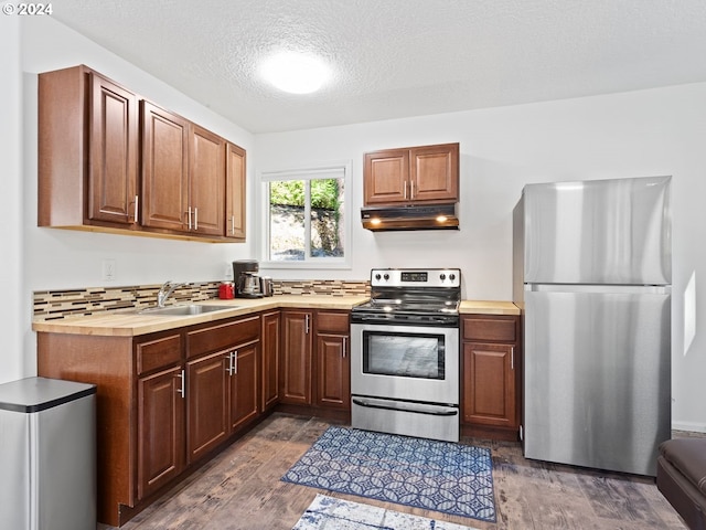 kitchen with stainless steel appliances, dark hardwood / wood-style flooring, sink, tasteful backsplash, and a textured ceiling